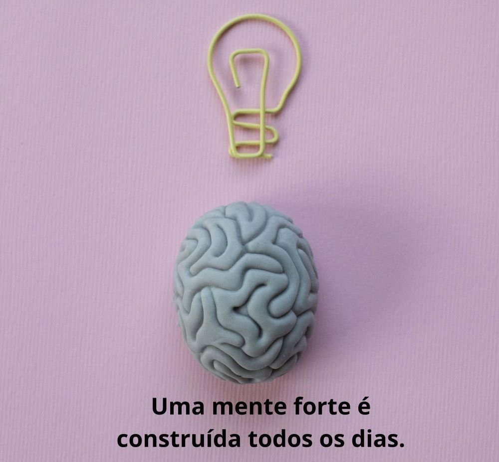 Ilustração de um cérebro cinza sobre um fundo rosa, com um clipe em formato de lâmpada acima, simbolizando inteligência e desenvolvimento mental. Na parte inferior, a frase: "Uma mente forte é construída todos os dias."