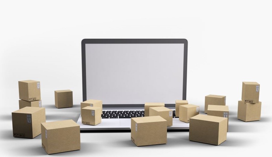 compras online com várias caixas ao redor de um notebook representando gastos invisíveis e consumo digital