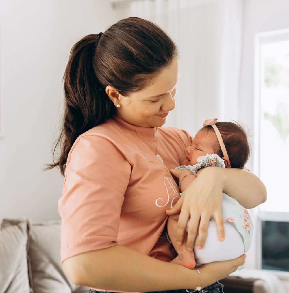 Mãe segurando bebê recém-nascido no colo em casa