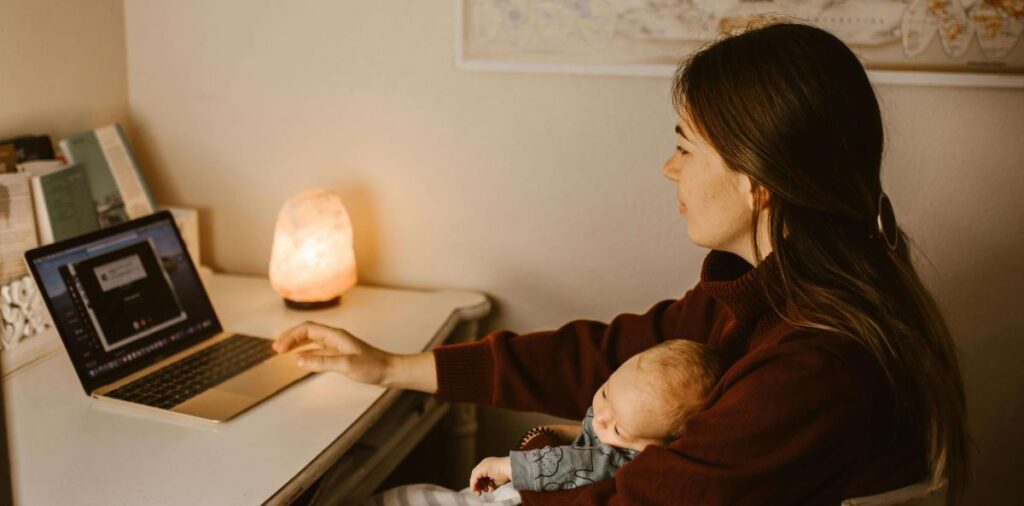 mãe solo trabalhando em casa com filho enquanto usa laptop