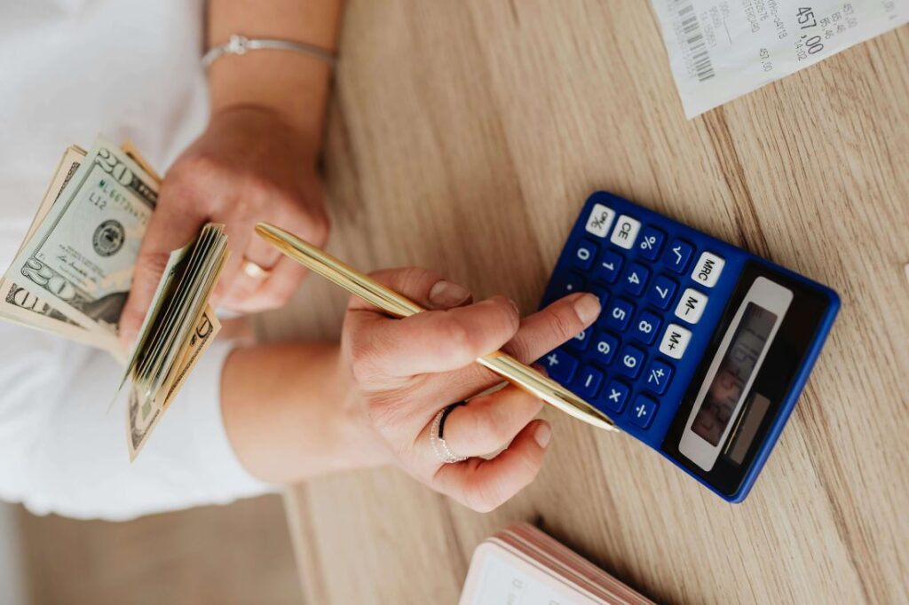 Pessoa calculando rendimento de investimento com dinheiro e calculadora