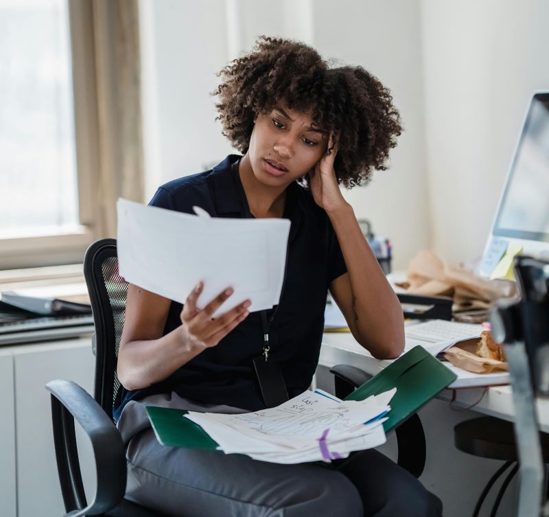 Mulher preocupada com contas atrasadas e dificuldades financeiras.