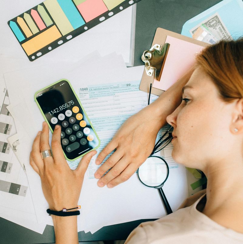 “Mulher preocupada analisando contas e calculadora enquanto organiza dívidas”