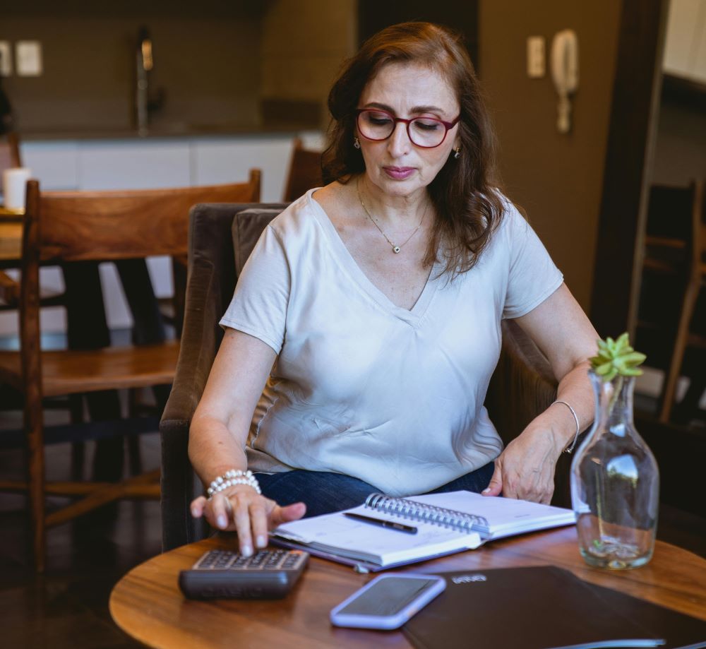 “Mulher fazendo planejamento financeiro em casa com calculadora e caderno”