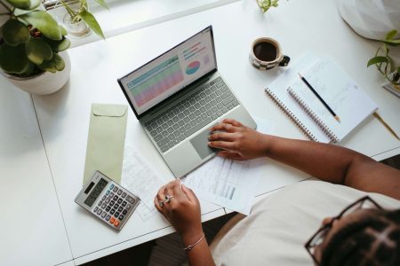 Pessoa analisando gráficos financeiros no computador planejando investimentos.