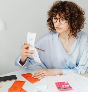 “Mulher analisando recibos e contas enquanto organiza dívidas e orçamento”